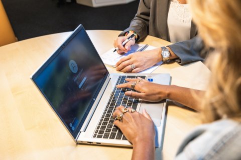 Medewerkers gezamenlijk achter een laptop. Communicatie, merk